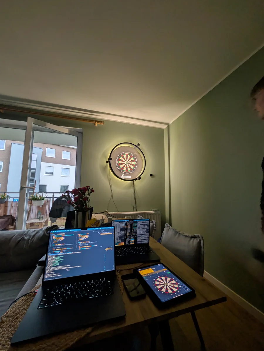 Datsu development workspace with laptops, a tablet, and a connected dartboard